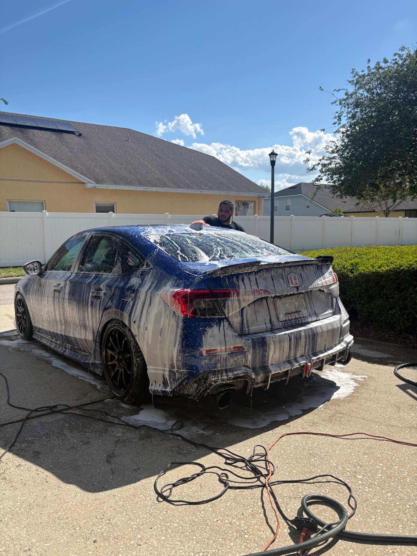 Rear view of a blue Honda Civic Si covered in foam during a hand wash
